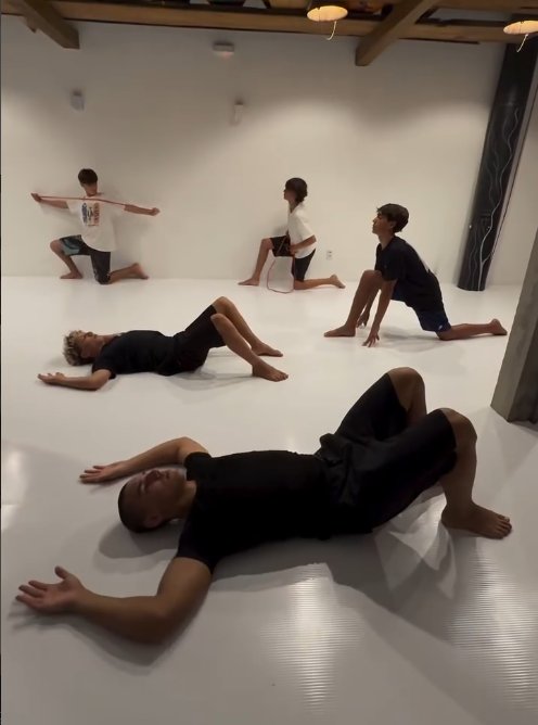Grupo fazendo exercícios de mobilidade no chão do estúdio